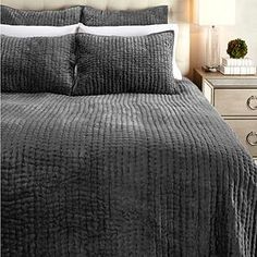 a bed with grey bedspread and two nightstands