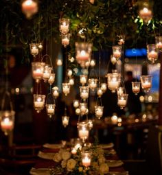 a long table with candles hanging from it's ceiling and plates on the table