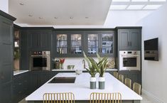 a large kitchen with green cabinets and white counter tops is pictured in this image, there are four chairs around the center island