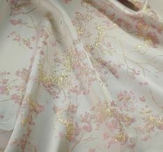 the fabric has pink flowers and gold leaves on it, along with a pair of scissors