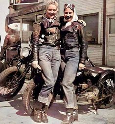 two women standing next to each other on motorcycles