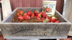 a wooden crate filled with strawberries next to a can