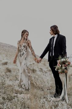 a bride and groom holding hands in a field