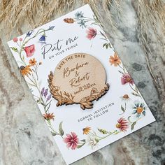 a wooden save the date magnet with flowers on it sitting on top of a marble surface