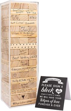 a wooden block tower with writing on it and a sign that says please sign black and white