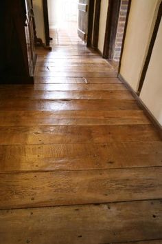 an empty hallway with wooden floors and white walls