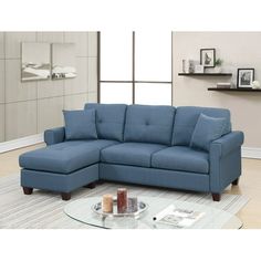 a blue sectional sofa sitting on top of a rug in a living room next to a glass table