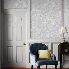 a blue chair sitting in front of a white wall with a yellow pillow on it