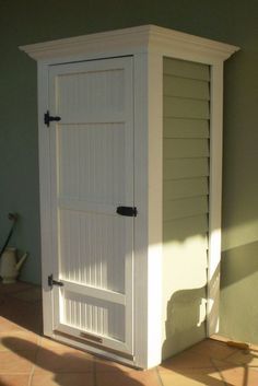 a white storage cabinet sitting on top of a tiled floor