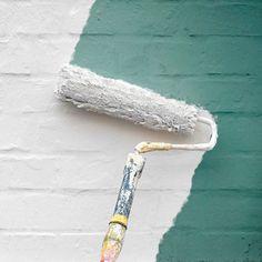 a paint roller is being used to paint a brick wall with green and white colors