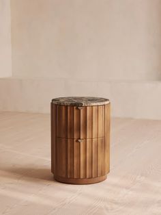 a wooden table with a marble top on the floor in front of a white wall