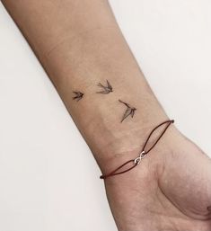 a woman's wrist with three small birds on the left side of her arm