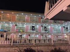 an apartment building with pink shutters and white balconies lit up at night