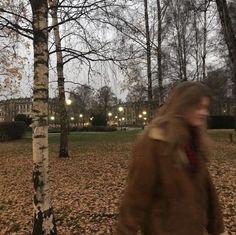 a blurry image of a person walking in the park with trees and leaves on the ground