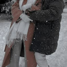 two people standing in the snow hugging each other