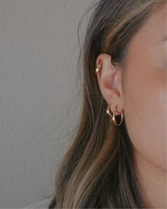 a close up of a person's ear with two small gold hoops on it