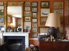 a living room with pictures on the wall and a lamp in front of a fireplace