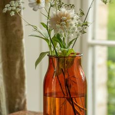 a vase filled with flowers sitting on top of a wooden table next to a window