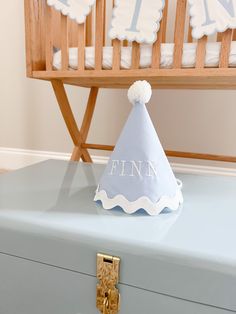 a baby's first birthday party hat sitting on top of a blue suitcase in front of a crib