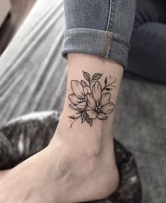 a black and white flower tattoo on the ankle