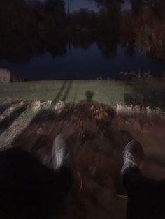 a blurry image of two people walking down a path at night with trees and water in the background