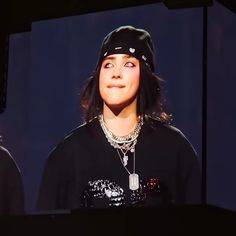 a woman wearing a black shirt and hat on top of a stage with her eyes closed