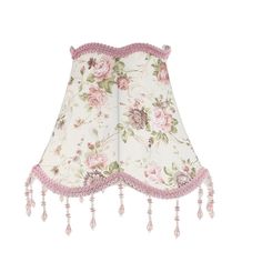 a white lamp shade with pink flowers and tassels on the bottom of it