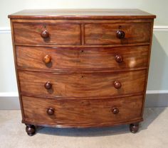 a wooden dresser with several drawers and knobs on the bottom drawer, in a room