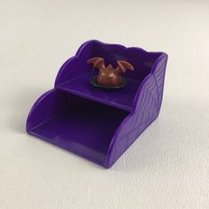 a small purple shelf with a figurine in it on a white table top