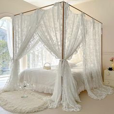 a canopy bed with sheer curtains and white bedspread