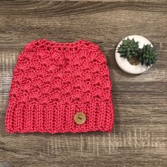 a red knitted hat next to a small plant