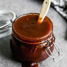 a jar of barbecue sauce with a wooden spoon in it