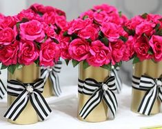 pink flowers in gold vases tied with black and white ribbon