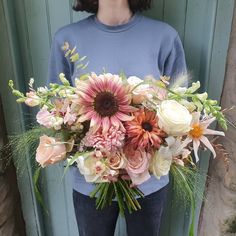 a woman standing in front of a door holding a bouquet of flowers