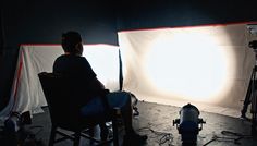 a man sitting in a chair with a light behind him and a camera next to him