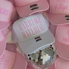 a pink hat with the words marriage material printed on it and disco ball in front