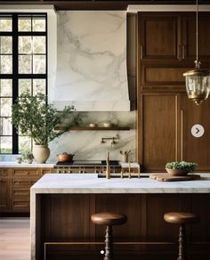 a kitchen with marble counter tops and wooden cabinets, two stools in front of the sink