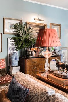 a living room filled with furniture and a lamp on top of a wooden table next to a couch