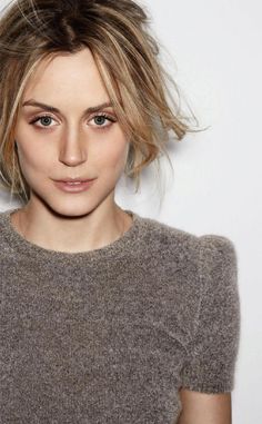 a close up of a person wearing a sweater and looking at the camera with a serious look on their face