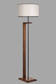 a lamp with a wooden base and a white shade on the top is standing in front of a gray background