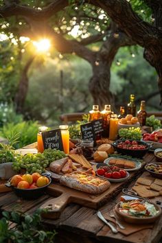 a wooden table topped with lots of food next to a lush green forest filled with trees