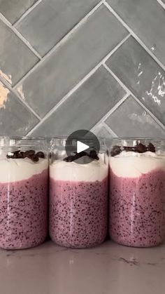 three jars filled with food sitting on top of a counter next to a tile wall