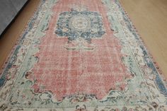 an old rug is laying on the floor in front of a wooden flooring area