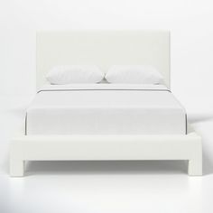 a white bed with two pillows on top of it