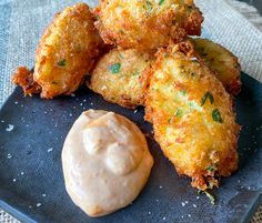 some fried food is sitting on a plate with a dipping sauce in front of it