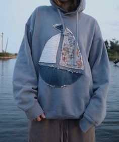 a person wearing a blue sweatshirt with a sailboat on it