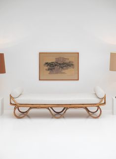 a white couch sitting next to two lamps on top of a wooden table in front of a painting