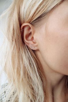 a woman with long blonde hair wearing a pair of ear piercings on her ears