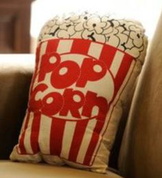 a red and white popcorn pillow sitting on top of a couch