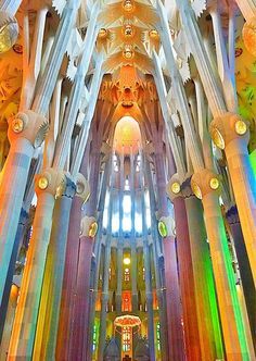 the inside of a large cathedral with many columns and colorful lights on it's ceiling